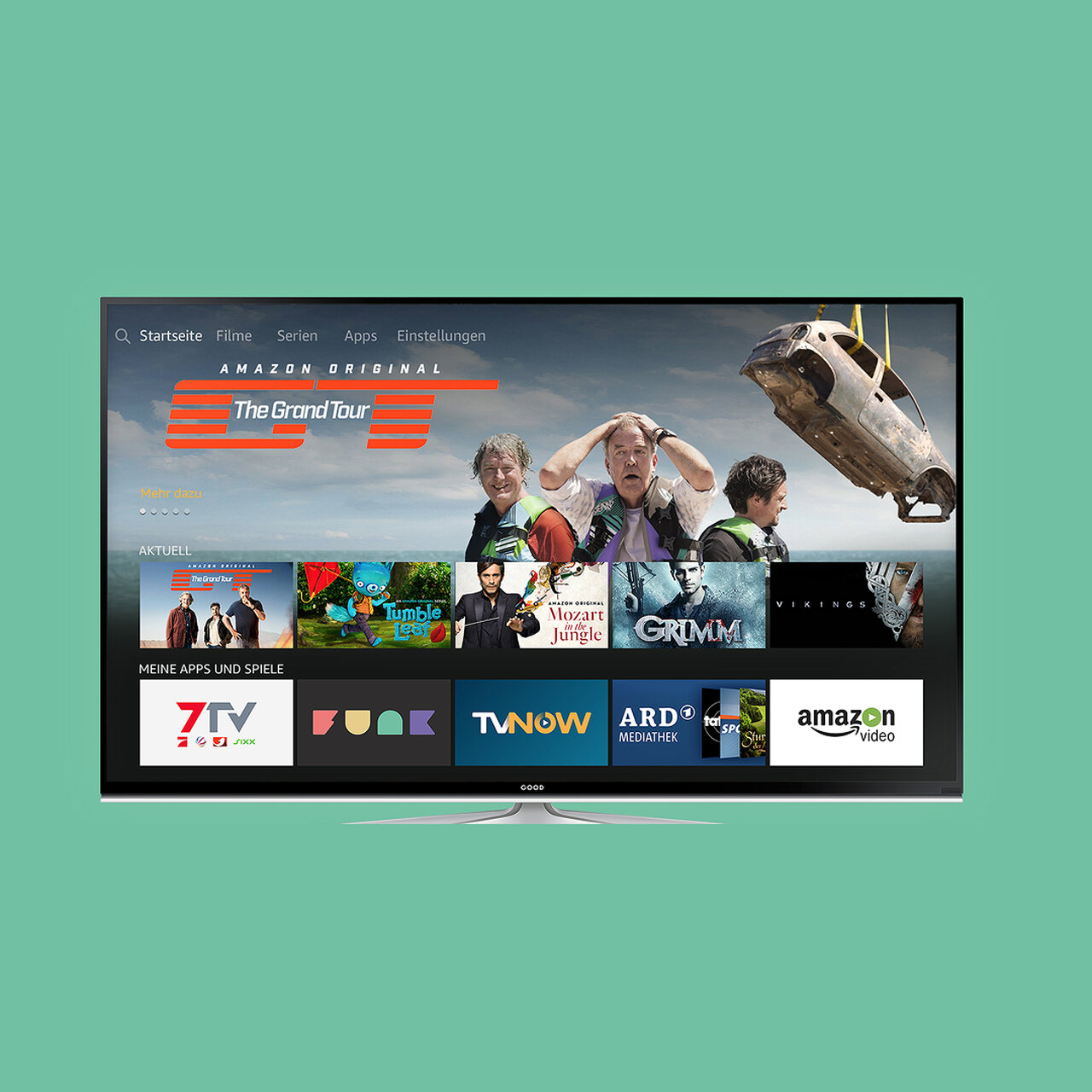 Smart-TV-Bildschirm mit Streaming-Plattform-Benutzeroberfl&auml;che. Mehrere Streaming-Dienste wie TV Now, Amazon Video und ARD sind sichtbar, mit einem Trailer f&uuml;r "The Grand Tour" im Hintergrund. Der Fernseher steht vor einem t&uuml;rkisfarbenen Hintergrund.