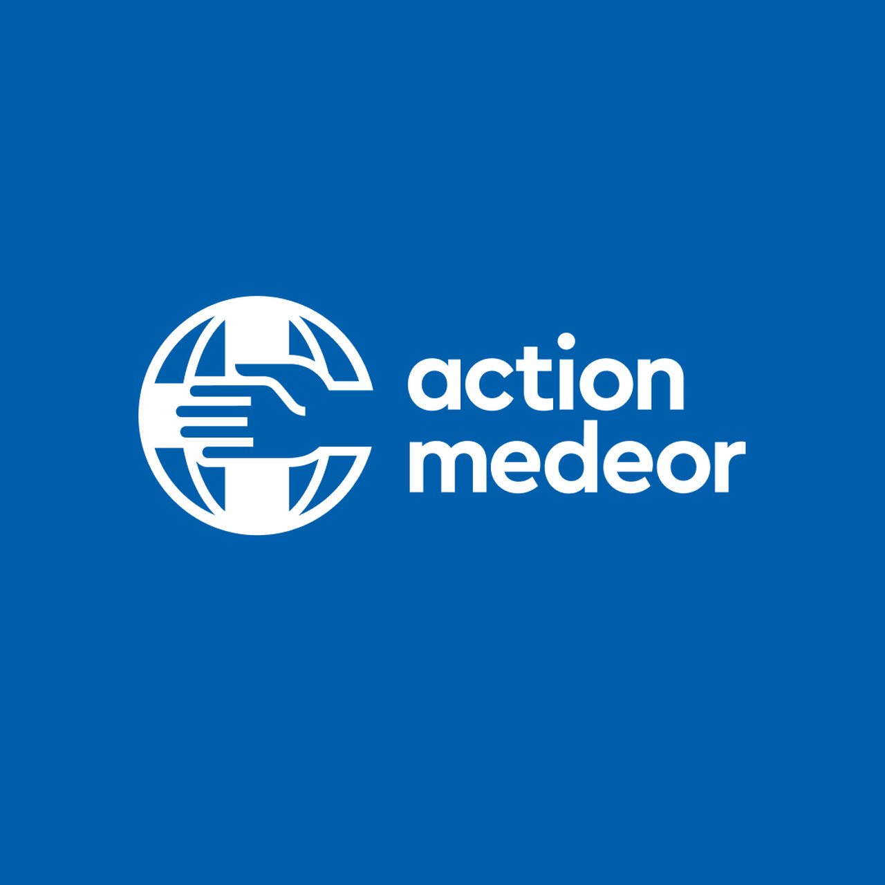 Rundes Logo von Action Med&eacute;or mit stilisiertem Globus und H&auml;nden, die einen Ausschnitt des Kreises bilden. Das Logo in Wei&szlig; auf blauem Hintergrund zeigt eine internationale humanit&auml;re Organisation.