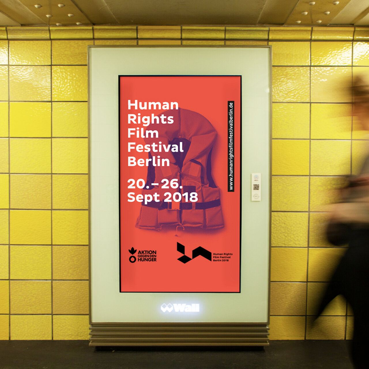Plakat f&uuml;r das Human Rights Film Festival Berlin vom 20. bis 26. September 2018. Das Design zeigt einen roten Hintergrund mit wei&szlig;er Typografie und einer stilisierten, geb&uuml;ckten menschlichen Silhouette in Dunkelrot, aufgeh&auml;ngt in einem gelben U-Bahnhof.
