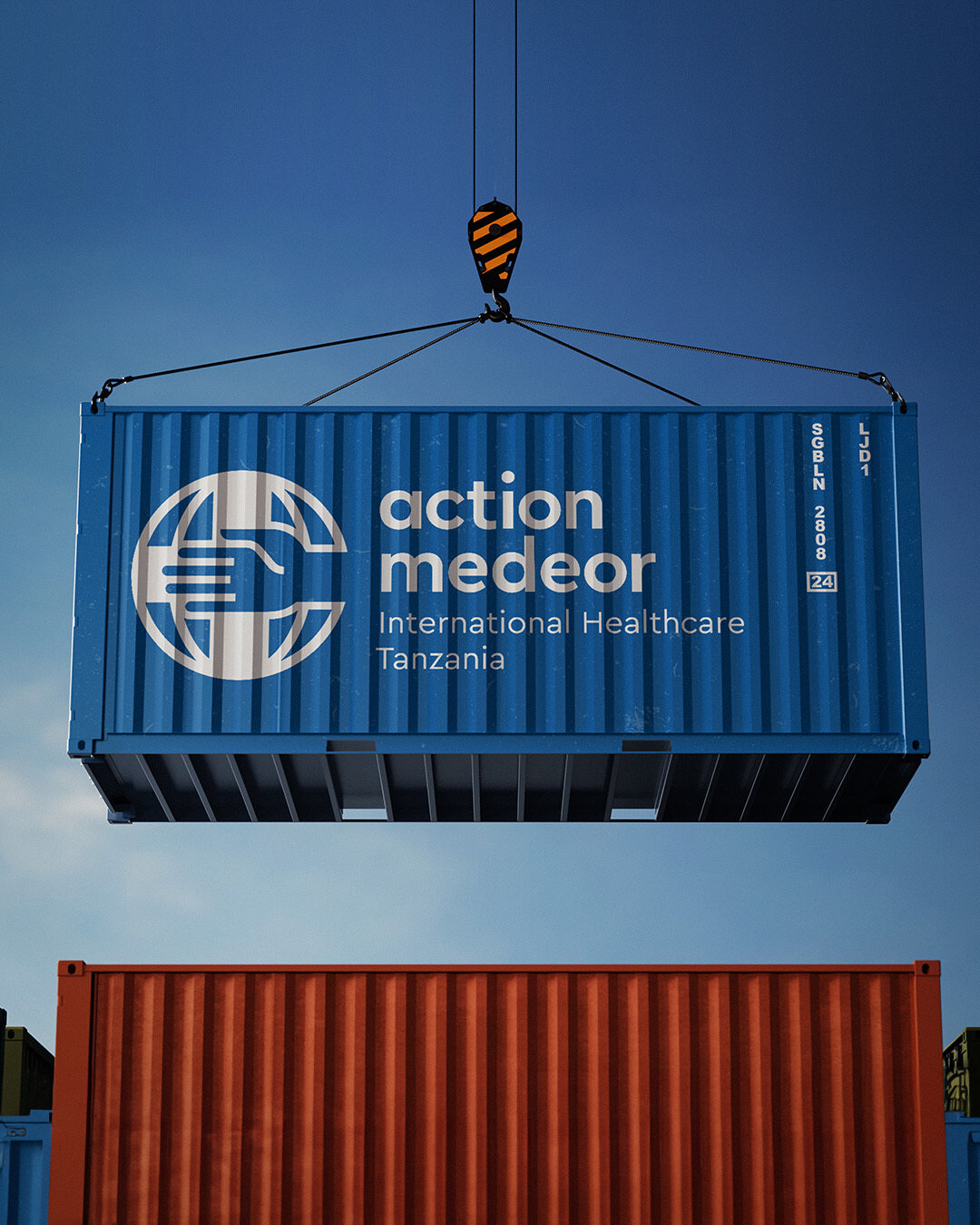 Blauer Seecontainer mit dem Logo und Schriftzug von Action Medeor International Healthcare Tanzania, der von einem Kranhaken an einem blauen Himmel gehangen wird, mit einem roten Container im Hintergrund.