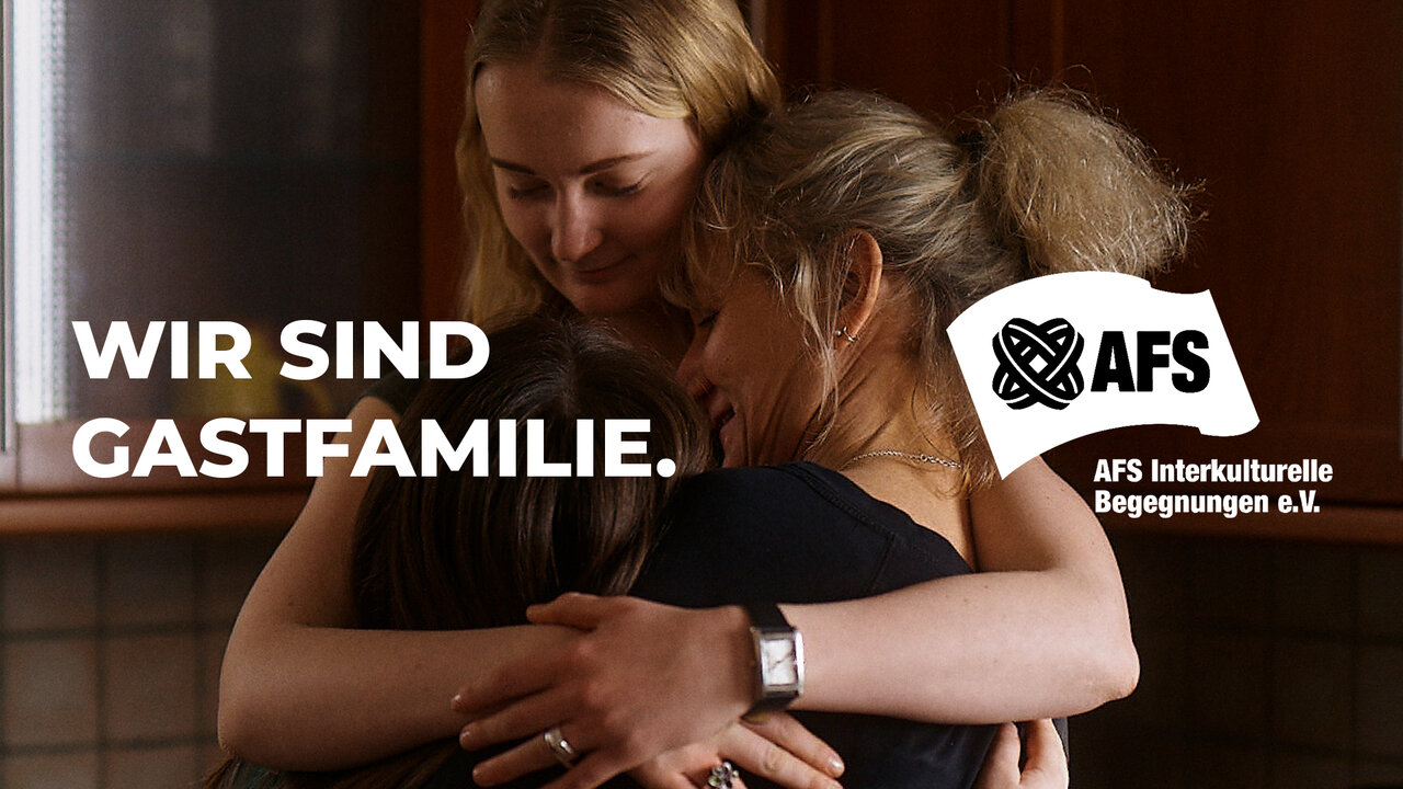 Zwei Menschen umarmen sich herzlich vor einem dunklen Hintergrund. Der AFS-Slogan "Wir sind Gastfamilie" und das AFS-Logo sind eingeblendet, was auf ein Programm f&uuml;r interkulturelle Begegnungen hinweist.