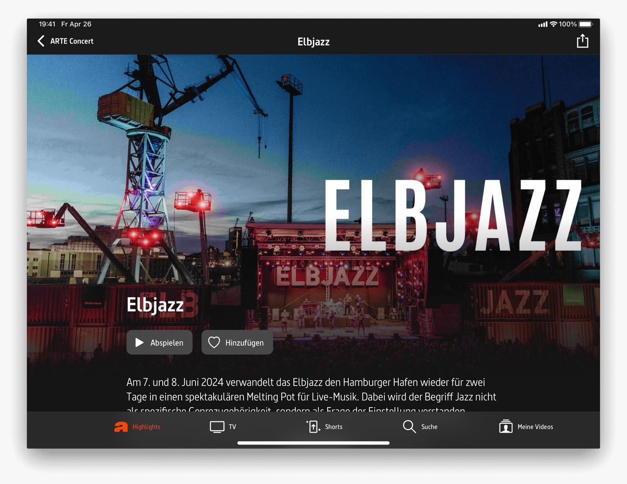 Abendliche Ansicht des Elbjazz-Festivals mit Hafenkran und beleuchteten Geb&auml;uden, gro&szlig;er wei&szlig;er Schriftzug "ELBJAZZ" vor n&auml;chtlichem Industrieszenario in Hamburg.