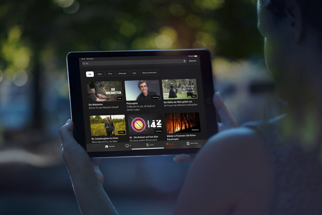 Eine Tablet-Ansicht der ARTE-App mit verschiedenen Videominiaturen und Sendungsvorschauen, die auf einem geblockten Hintergrund pr&auml;sentiert werden. Die App zeigt ein klares, modernes Design mit Videoinhalten in einem Rasterformat.