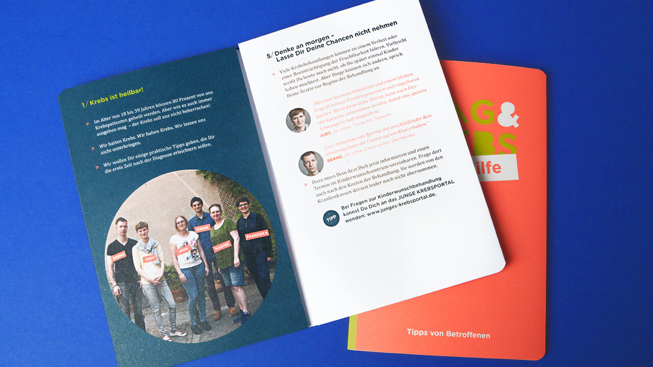 Eine Brosch&uuml;re von Studio Good liegt aufgeschlagen auf blauem Hintergrund, zeigt eine kreisrunde Gruppenaufnahme mehrerer junger Menschen und eine Seite mit Text und Profilbildern, in Orange- und Gr&uuml;nt&ouml;nen gehalten.