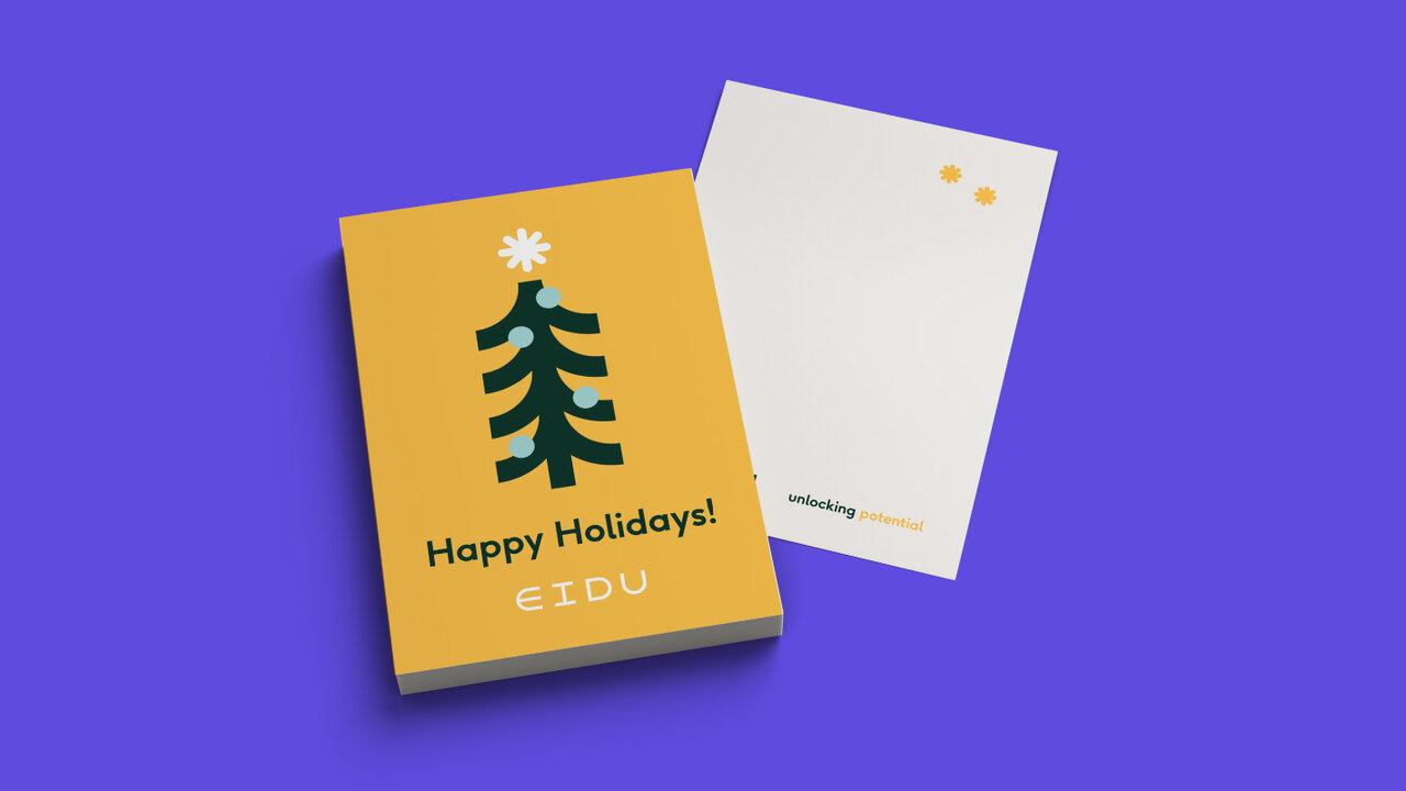 Eine gelbe Gru&szlig;karte mit einem stilisierten Weihnachtsbaum und dem Text "Happy Holidays! CIDU" liegt auf einem lila Hintergrund, daneben eine wei&szlig;e R&uuml;ckseite der Karte.