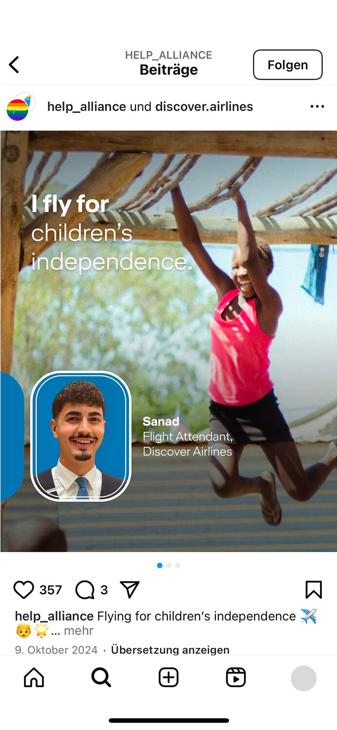 Ein Flugbegleiter von Discover Airlines mit blauem Rahmen l&auml;chelt neben einem springenden Kind in einem Raum mit Holzbalken. Der Text "I fly for children's independence" unterstreicht die Botschaft der Help Alliance f&uuml;r Kinderrechte.