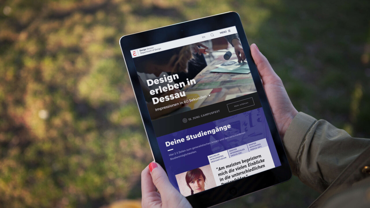 Tablet-Bildschirm zeigt Website-Design f&uuml;r die Hochschule Anhalt mit blau-grauem Layout, pr&auml;sentiert vor unscharfem Hintergrund. Webseite pr&auml;sentiert Design und Studienangebote der Hochschule Anhalt mit klarer Navigationsstruktur.