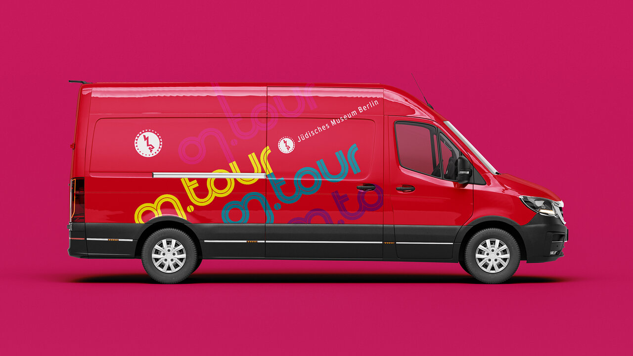 Roter Transporter mit dem Logo und Schriftzug "on.tour" des J&uuml;dischen Museums Berlin vor einem knallrosa Hintergrund, als Teil einer mobilen Bildungsausstellung zur j&uuml;dischen Geschichte, Kultur und Religion.