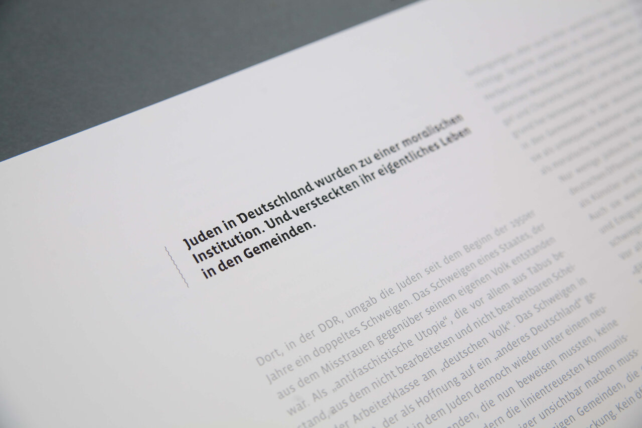 Nahaufnahme einer aufgeschlagenen Buchseite mit deutschem Text &uuml;ber j&uuml;disches Leben in Deutschland, auf grau-wei&szlig;em Hintergrund.