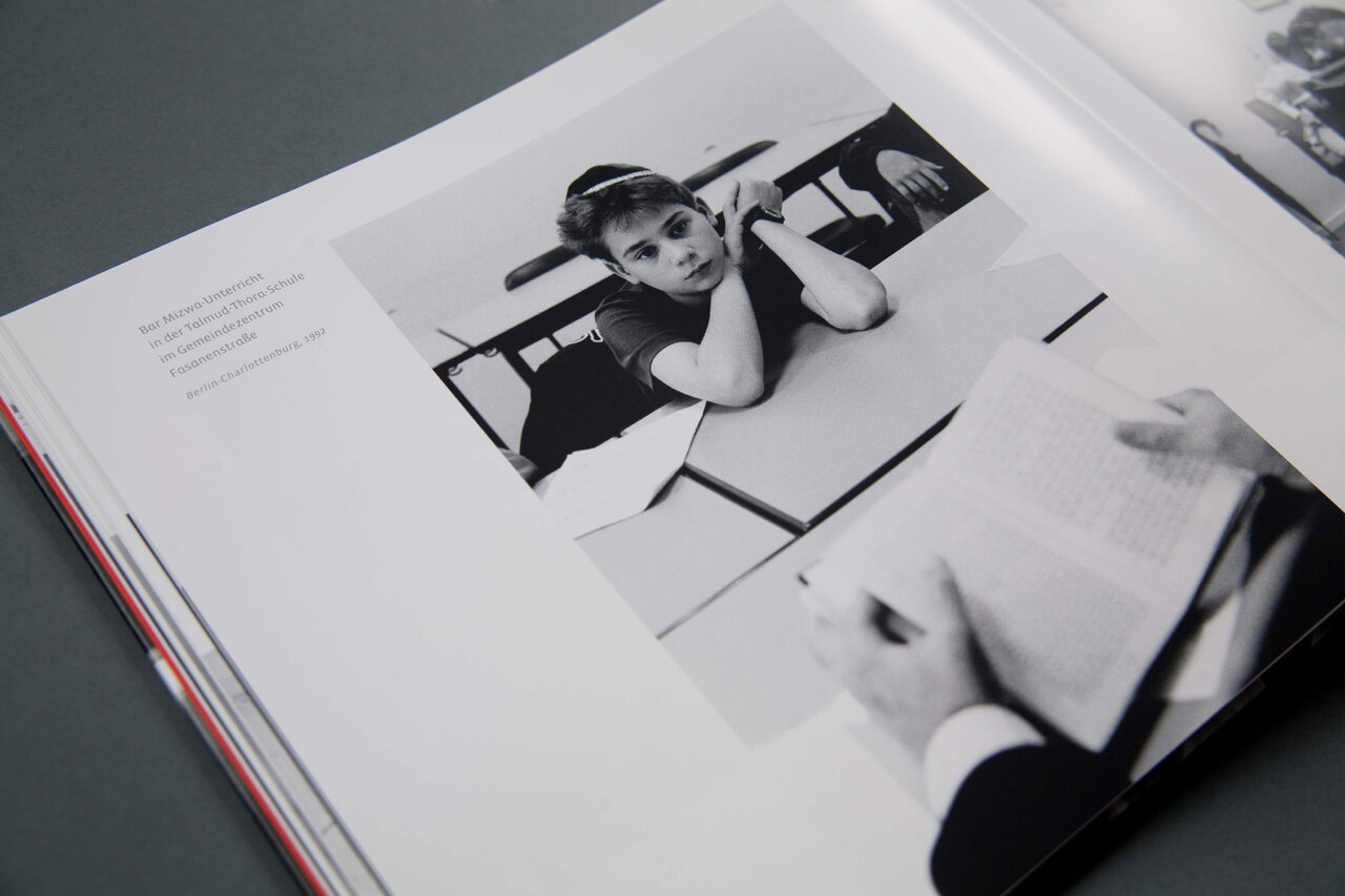 Schwarzwei&szlig;fotografie einer Person in einem ge&ouml;ffneten Buch, die l&auml;ssig &uuml;ber einer grafischen Komposition liegt, mit einer minimalistischen, zur&uuml;ckhaltenden Gestaltung, die die Aufmerksamkeit auf die Bildsprache lenkt.