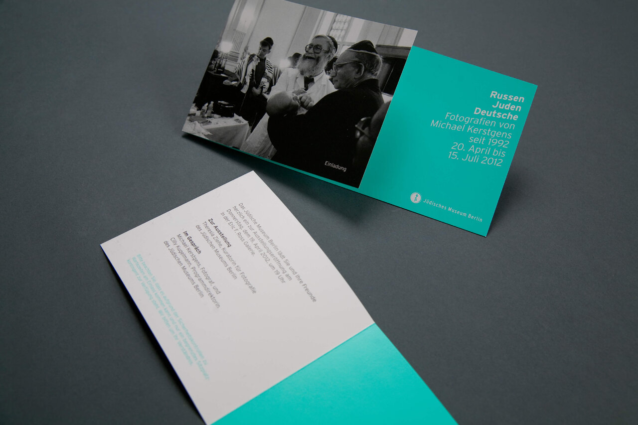 Zwei Brosch&uuml;ren oder Publikationen in T&uuml;rkis und Wei&szlig;, die Teil eines Projekts &uuml;ber j&uuml;disches Leben in Deutschland sind, mit einer schwarzwei&szlig;en Fotografie und gedruckten Informationen, pr&auml;sentiert auf einem grauen Hintergrund.