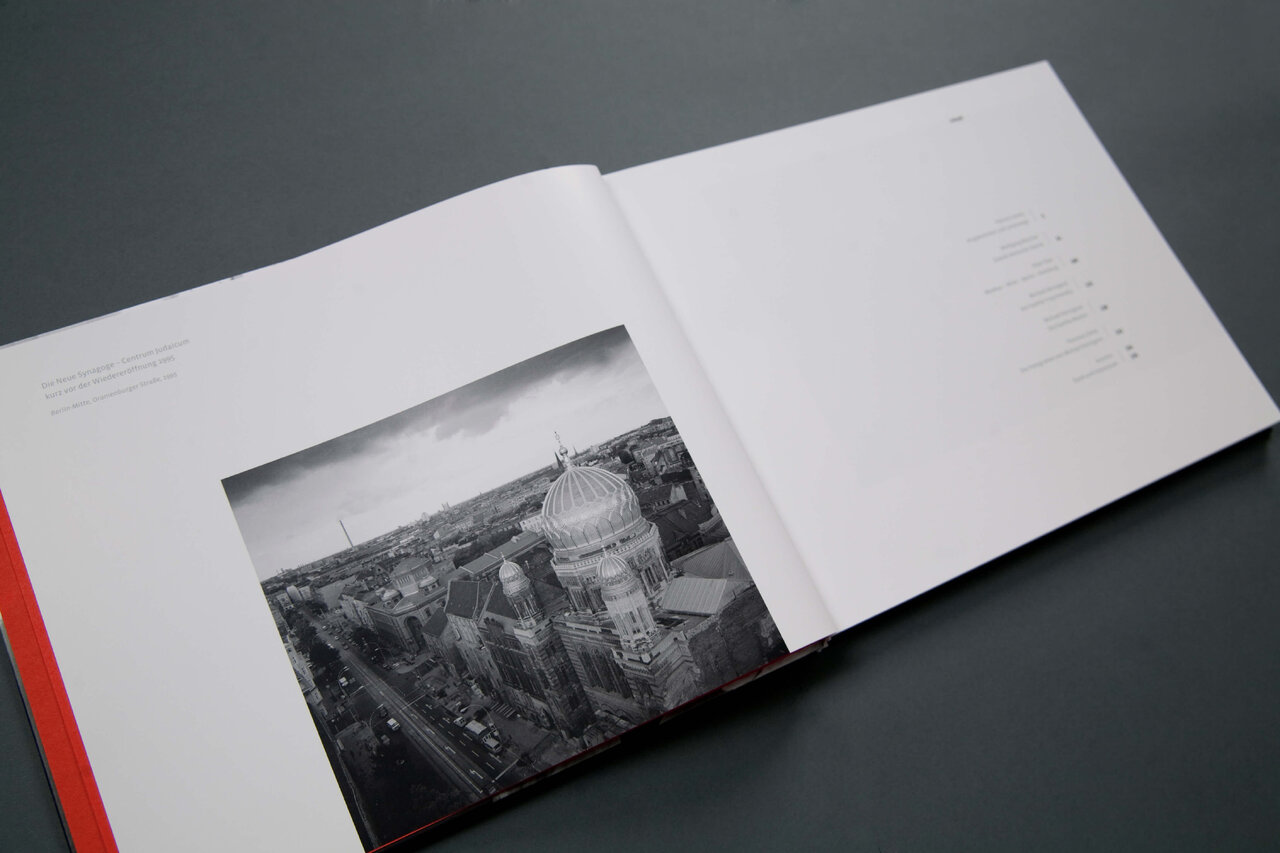 Eine schwarzwei&szlig;e Fotografie in einem aufgeschlagenen Buch, die eine Stadtlandschaft mit markanten Architekturdetails zeigt, eingebettet in ein minimalistisches Seitenlayout mit wei&szlig;em Hintergrund.