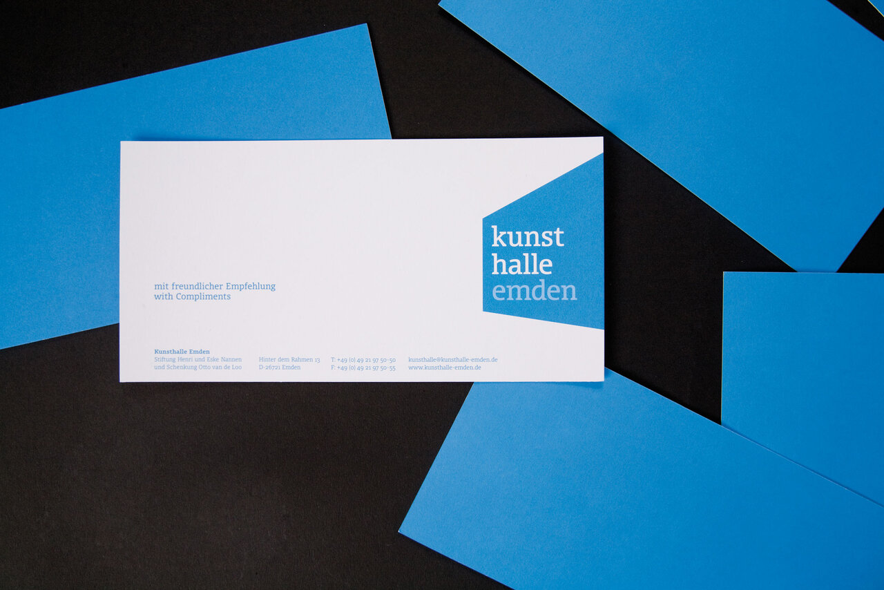 Gesch&auml;ftsausstattung der Kunsthalle Emden mit wei&szlig;er Karte und blau-schwarzem geometrischem Hintergrund. Das Design zeigt das neue Corporate Design mit klarer, moderner Formensprache und blauer Akzentuierung.
