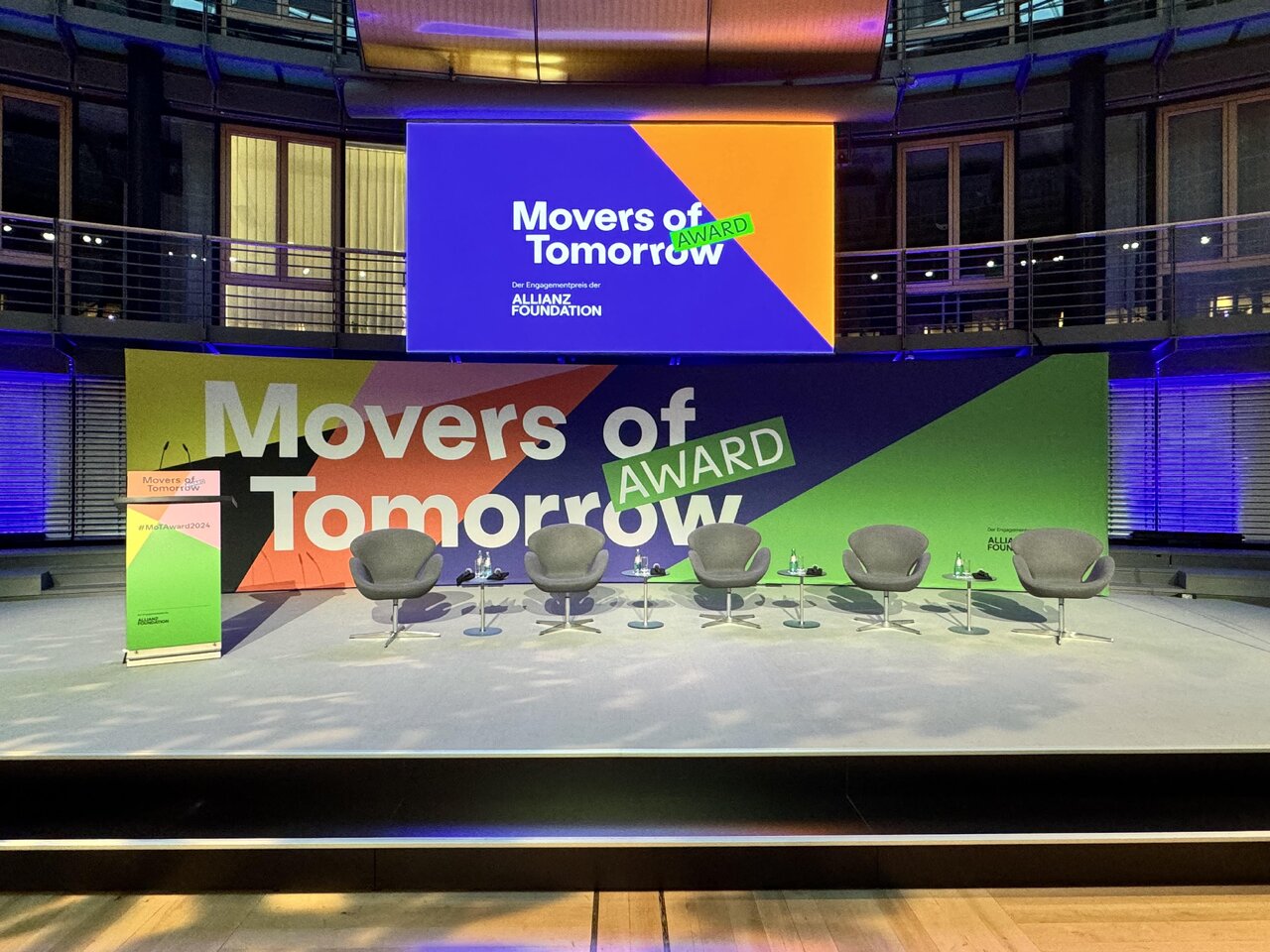 B&uuml;hnenaufbau f&uuml;r den "Movers of Tomorrow Award" mit gro&szlig;formatigen Bildschirmen und Sesseln, die die Markenidentit&auml;t in kr&auml;ftigen Farben und modernem Design pr&auml;sentieren.