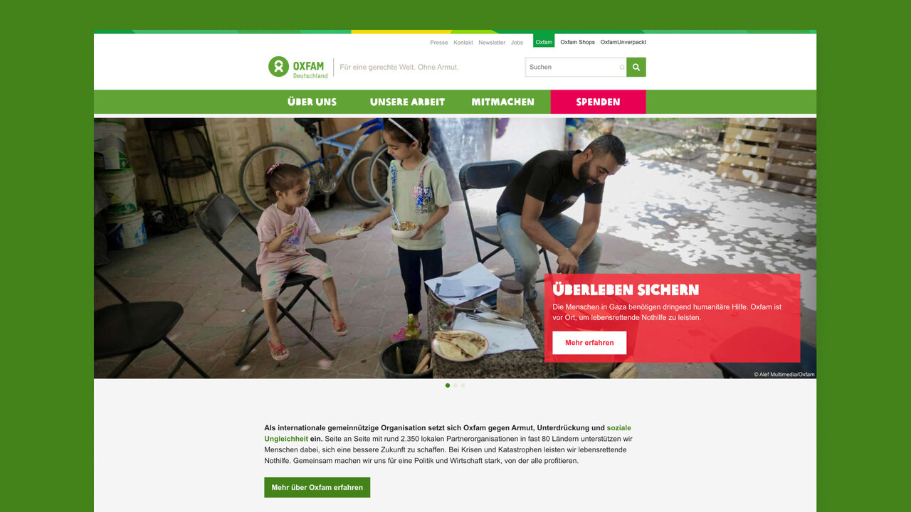 Zwei Personen in einem Raum mit Fahrrad, eine sitzt und eine steht, w&auml;hrend eine dritte Person an einem Tisch arbeitet, vor dem Hintergrund von gestapelten Materialien.