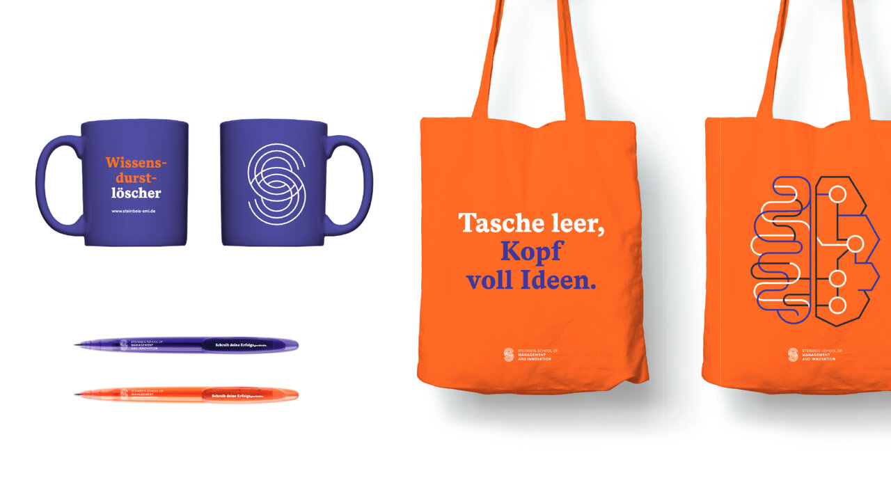 Zwei blaue Tassen und zwei orangefarbene Taschen von Studio Good mit verschiedenen grafischen Designs und Texten. Ein blauer und ein orangefarbener Stift erg&auml;nzen das Produktset. Die Taschen tragen den Slogan "Tasche leer, Kopf voll Ideen" in wei&szlig;er Schrift.