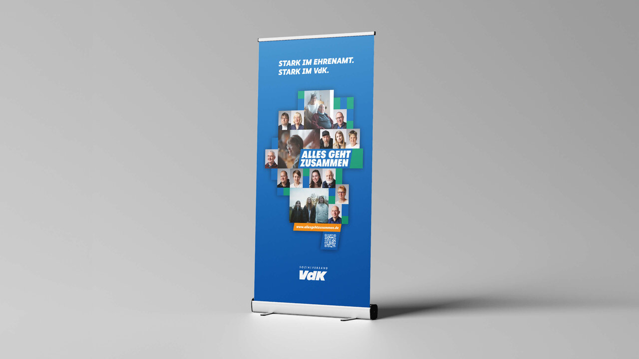 Blau-wei&szlig;es Rollup-Banner der VdK-Organisation mit Portr&auml;tfotos verschiedener Menschen, die ein Kreuz-Symbol bilden, symbolisiert Gemeinschaft und Solidarit&auml;t.