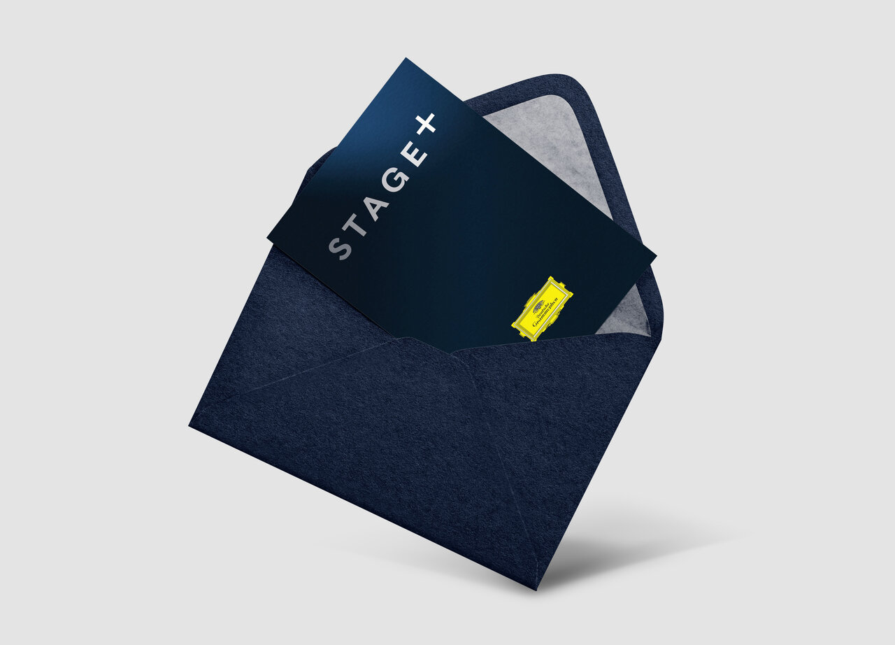 Schwarzer Umschlag-Mockup mit einer dunkelblau-wei&szlig;en Postkarte von Stage+, die leicht aus dem Umschlag herausragt und einen gelben Akzent tr&auml;gt.
