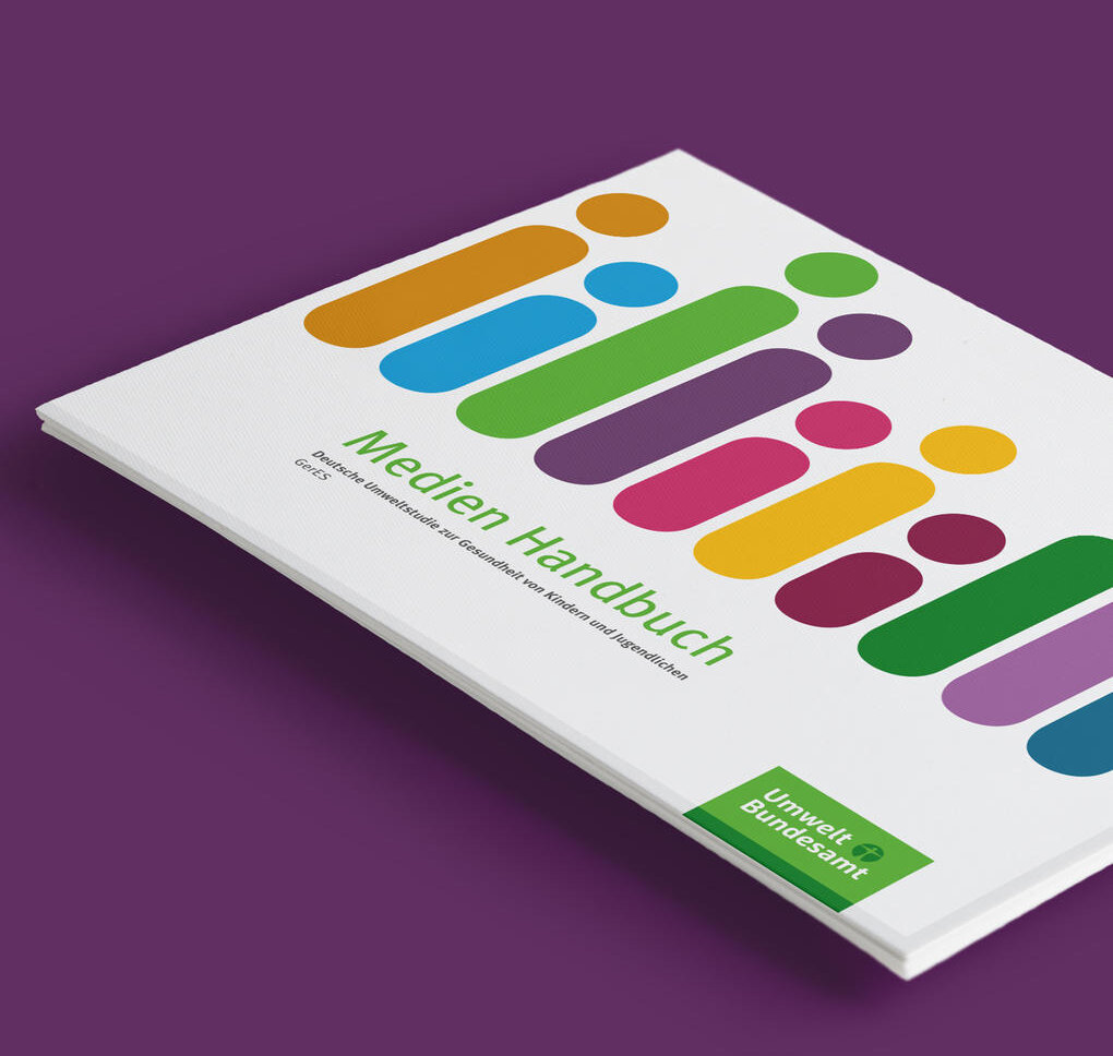 Medien Handbuch Buchcover in Wei&szlig; mit abstrakten, bunten vertikalen Formen in Gelb, Blau, Gr&uuml;n, Lila und Rosa vor violettem Hintergrund, pr&auml;sentiert in einer leichten Perspektive.
