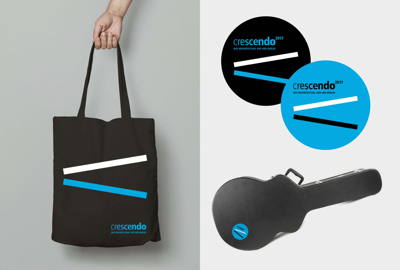 Drei Designelemente f&uuml;r das Musikfestival crescendo: eine dunkelgraue Einkaufstasche mit blau-wei&szlig;em Logo, zwei Kreislogos in Schwarz und Blau und ein schwarzer Gitarrenkoffer, alle mit dem minimalistischen crescendo-Branding versehen.